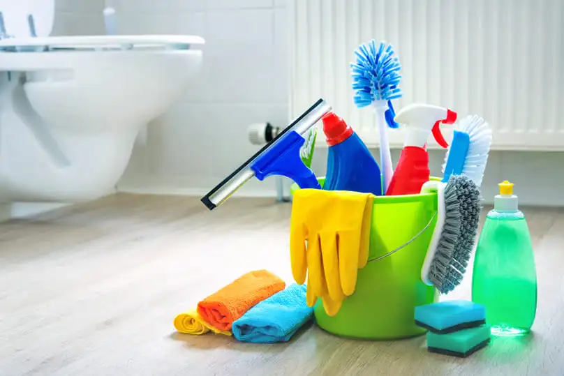 A bucket of cleaning supplies in a bathroom, illustrating what does deep cleaning include.