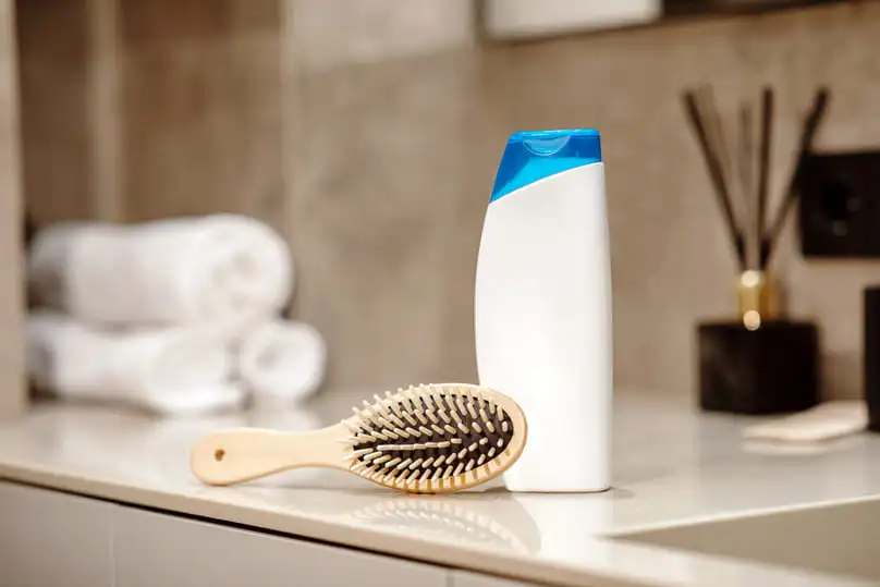 Bathroom counter with shampoo bottle and hairbrush, illustrating how to wash hair brushes.