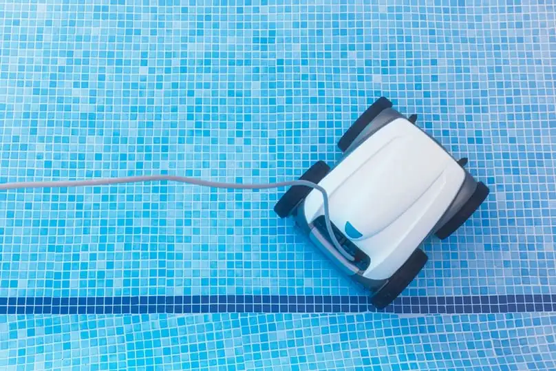 A swimming pool robot vacuum in a blue tiled pool, explaining how a swimming pool vacuum works.