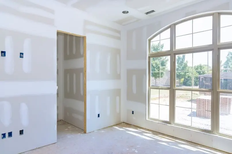 Newly built room with drywall and dust on the floor, showing how to clean construction dust from walls after renovation.