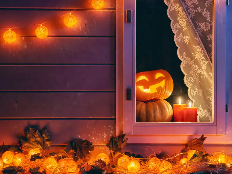 Illuminated pumpkins and candles in a window, after which one might need tips for storing Halloween decorations.