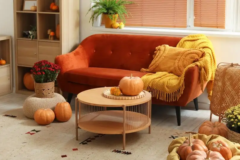 A living room decorated for fall with an orange sofa, anticipating spills that need how to clean carpet after Thanksgiving dinner.