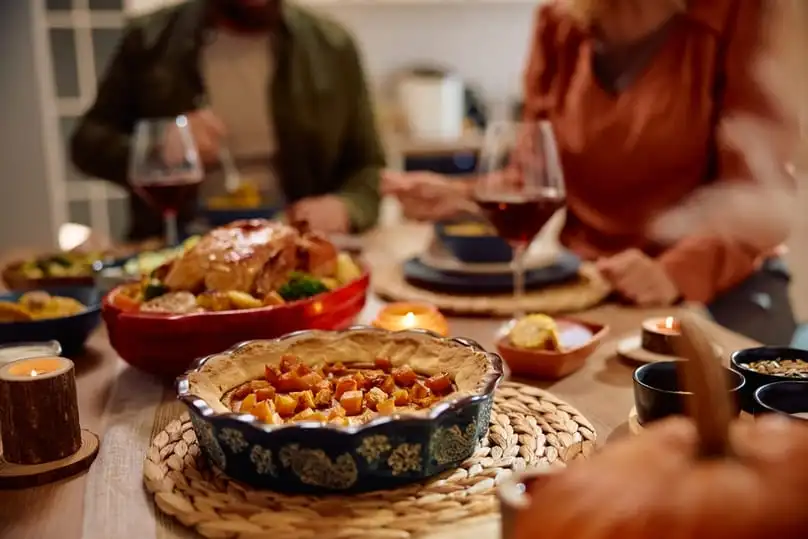 A festive holiday table with a pie and dinner, requiring preparation with a Thanksgiving Day checklist.