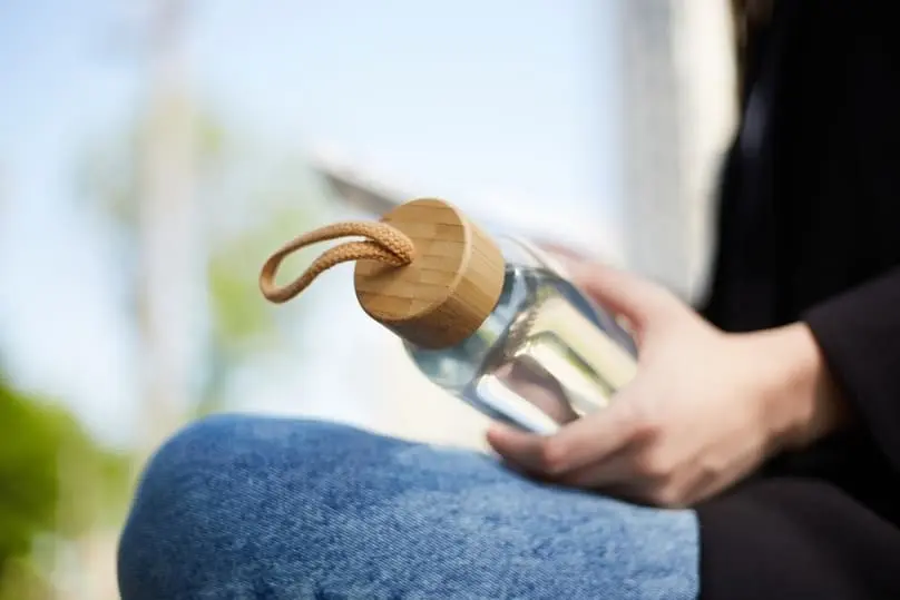 A person holds a water bottle with, suggesting the need for how to clean reusable water bottles.