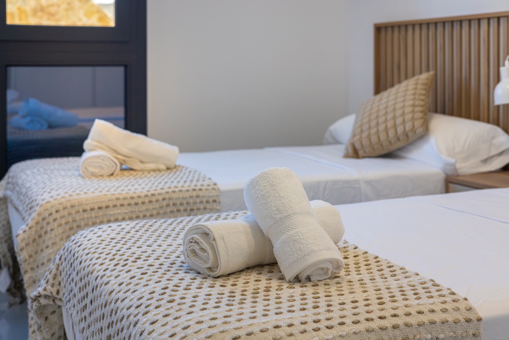 Freshly rolled white towels rest on a tidy bed, a final step on an Airbnb cleaning checklist.