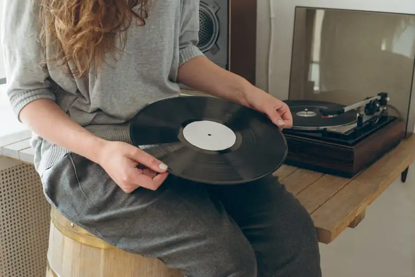 A woman holds a vintage album by its edges, demonstrating how to clean vinyl records safely.
