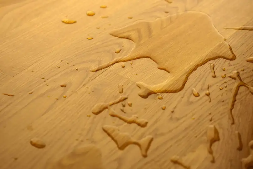 Water puddles on a wooden surface, showing the need for how to remove water stains from wood.