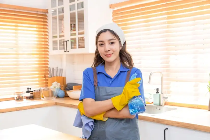 A smiling cleaner in a kitchen shows the benefits of property management cleaning services.