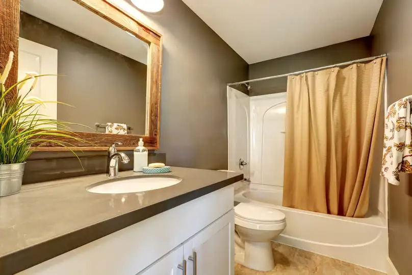 A clean white tub and modern vanity answering the question, why is my shower turning orange.