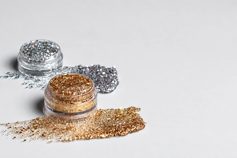 Two spilled jars of gold and silver sparkles highlight our tips on how to clean up glitter.